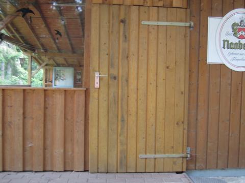geschlossene Holztür außen mit Schild daneben